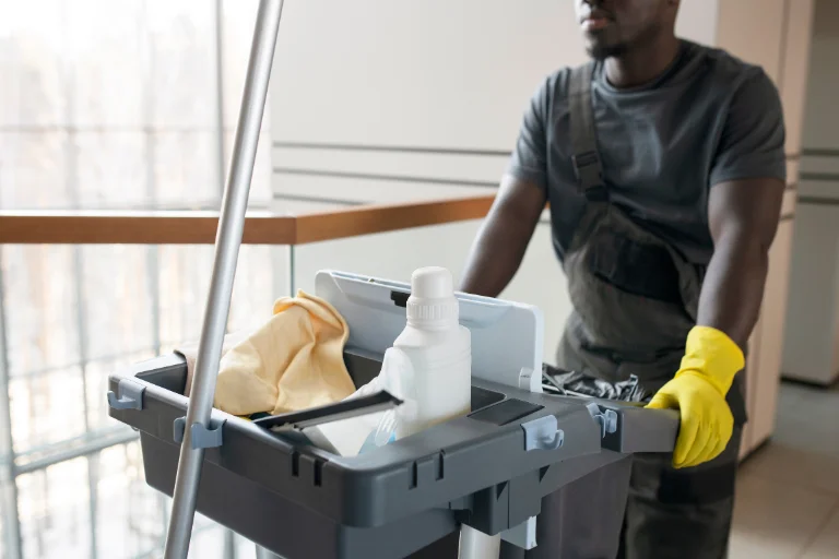 Carrinho de limpeza hospitalar com produtos, sendo empurrado por profissional com luvas amarelas, em artigo da SuperPro Bettanin.