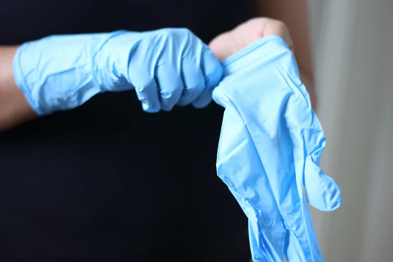 Pessoa vestindo luvas de latex azul para proteção, em um artigo da SuperPro Bettanin sobre luvas de vinil ou látex.
