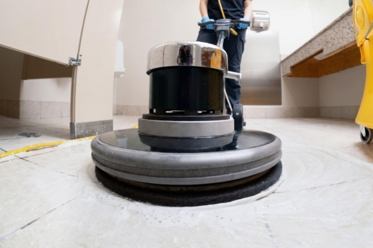 Máquina de limpeza profissional polindo piso de azulejo em banheiro, ilustrando conteúdo da SuperPro Bettanin sobre disco removedor.