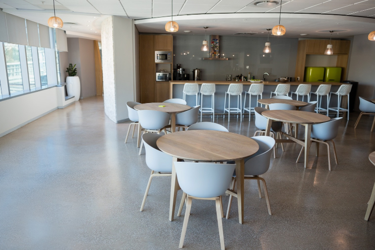 Vista de cafeteria com mesas e cadeiras posicionadas no salão, ilustrando um conteúdo da SuperPro Bettanin sobre NR-24.