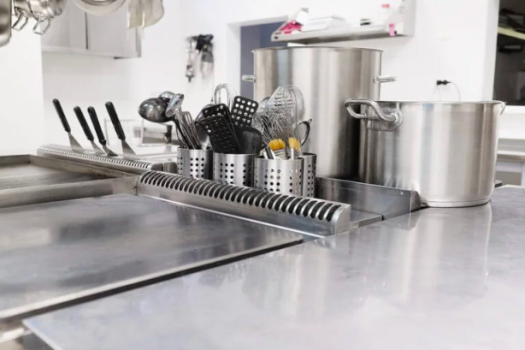Balcão de inox de cozinha industrial com chapas e utensílios