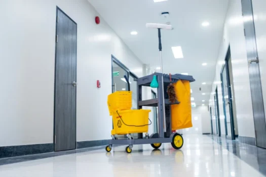 Carrinho de limpeza industrial amarelo localizado no centro de um corredor.