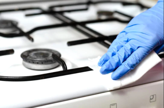 Close-up de mão com luva limpando fogão