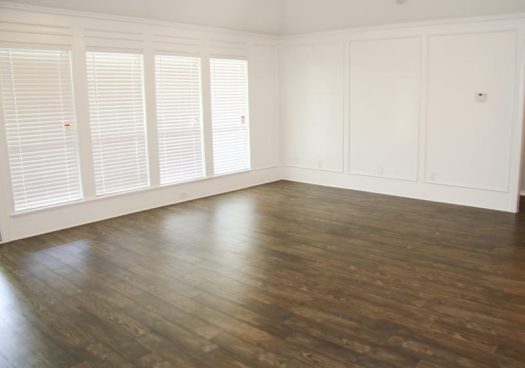 Cômodo vazio com paredes brancas e piso vinílico amadeirado