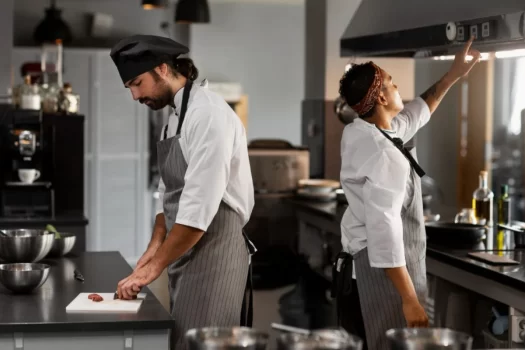 Cozinheiros preparando comida em uma cozinha profissional, normas da vigilância sanitária para bares e restaurantes.