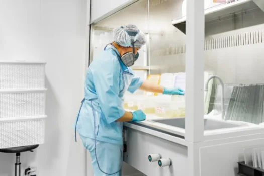 Profissional de laboratório usando máscara e luvas manipulando amostras, representando a desinfecção de alto nível para um artigo da SuperPro Bettanin.