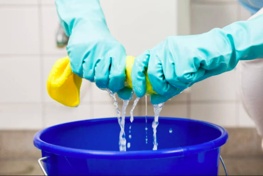 Mãos com luvas espremendo pano em balde