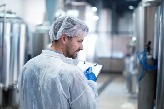 Técnico inspecionando indústria, representando o manual de higienização na indústria alimentar.